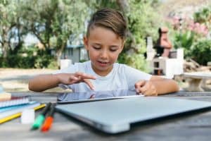 Studio Inglese Kid with tablet studying in garden