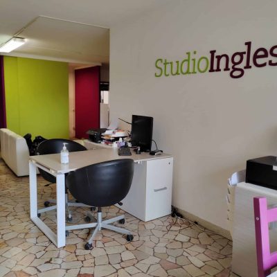 Reception area di Studio Inglese con scrivania, computer e sedie.